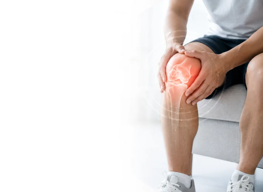 Man seated holding his knee, the painful joint highlighted